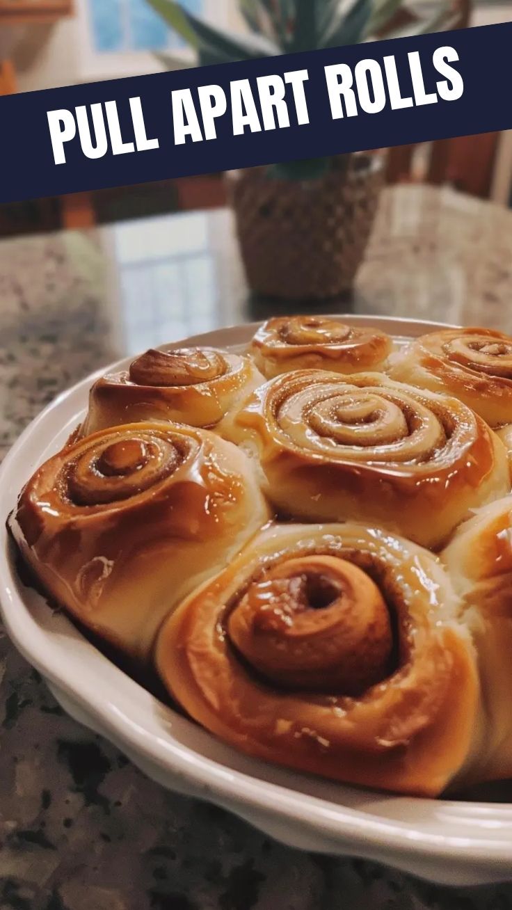 Freshly baked homemade cinnamon rolls with icing on a cooling rack.